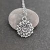 Close-up of a 3D silver pewter dahlia flower pendant on a stainless steel chain."
