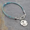 thin beaded bracelet with silver sand dollar charm