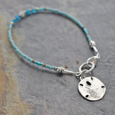 thin beaded bracelet with silver sand dollar charm