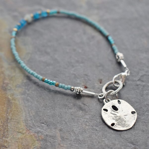 thin beaded bracelet with silver sand dollar charm