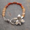 Beaded golds and dark oranges gemstone bracelet with silver Tigerlily flower clasp.